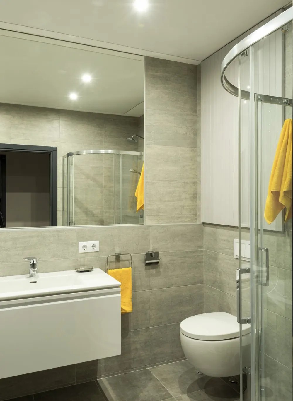 Baño compacto con mampara curva, mueble suspendido blanco e inodoro suspendido