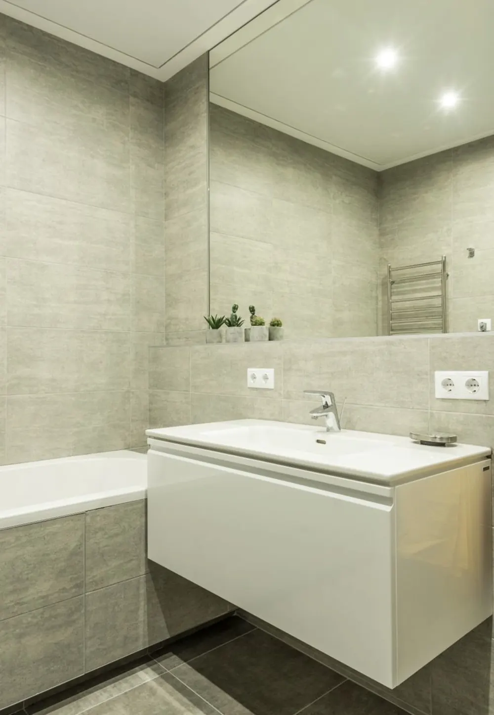 Baño en porcelánico gris piedra con bañera, mueble lacado y espejo a medida
