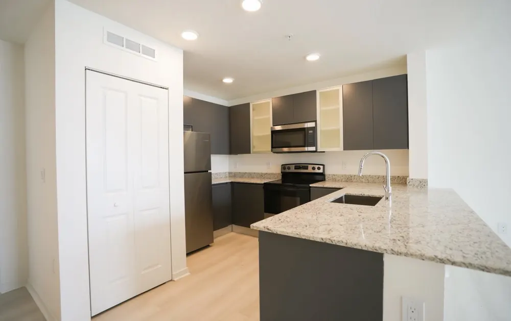 Cocina en L con encimera de granito y combinación de muebles blancos y grafito