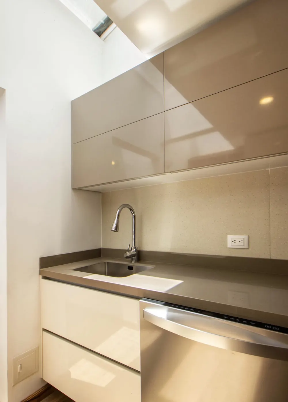 Cocina con muebles lacados en brillo, lucernario y fregadero bajo encimera