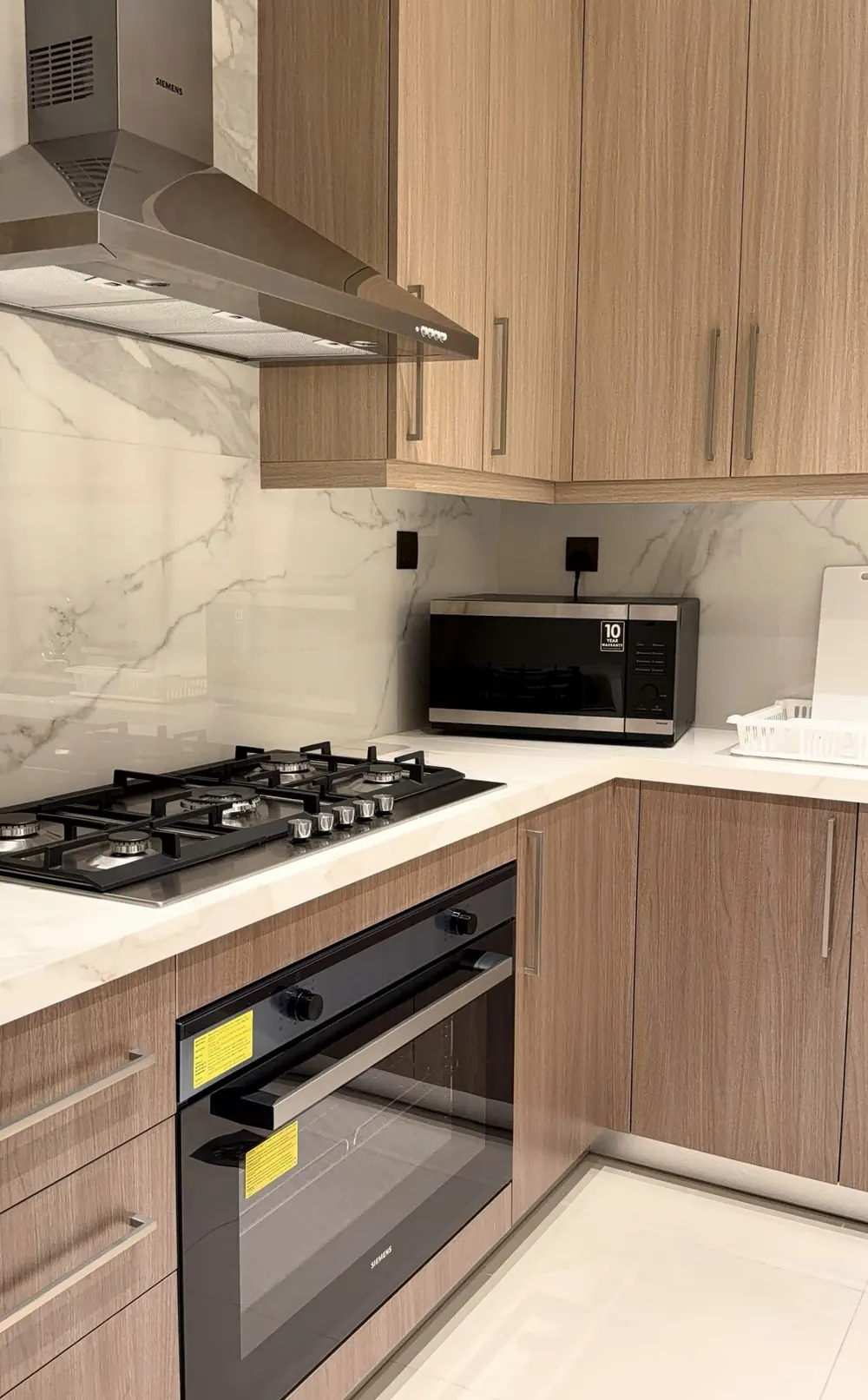 Cocina con muebles de madera natural, frontal efecto mármol y placa de gas de cinco fuegos