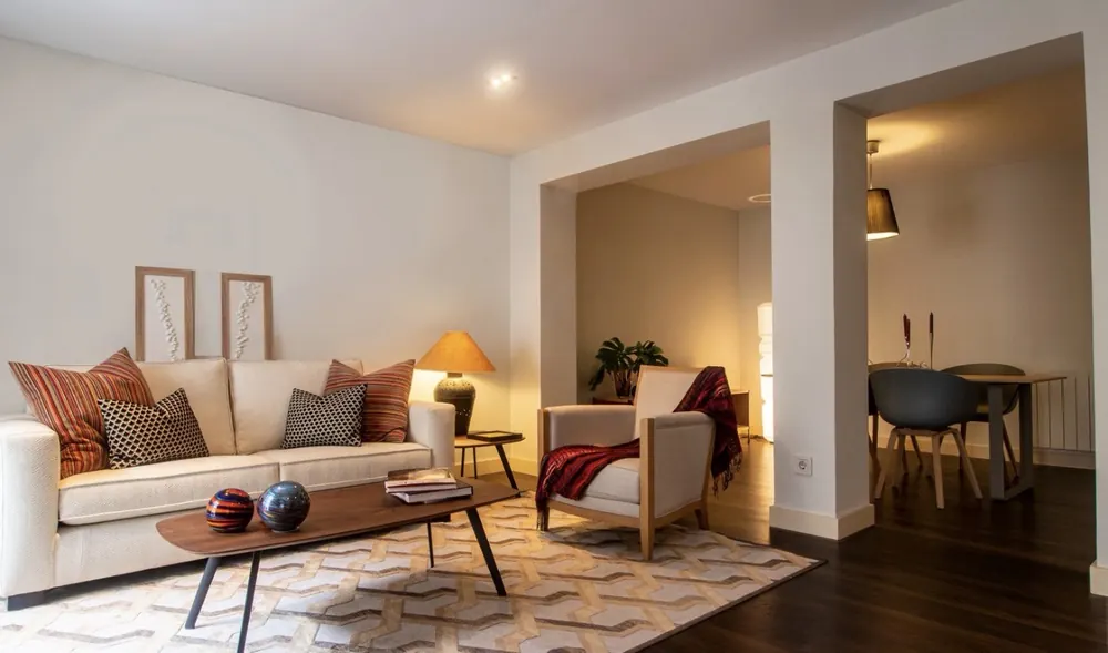 Salón y comedor en tonos cálidos con parquet oscuro y paso a comedor