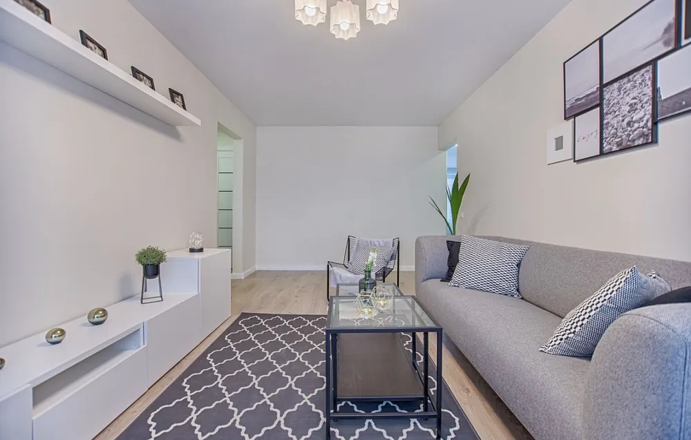 Salón de estilo nórdico con mueble volado blanco y alfombra geométrica