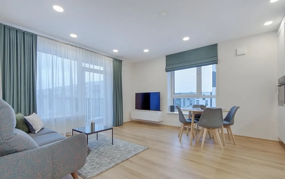Salón comedor con ventanal, cortinas de lino y suelo laminado claro